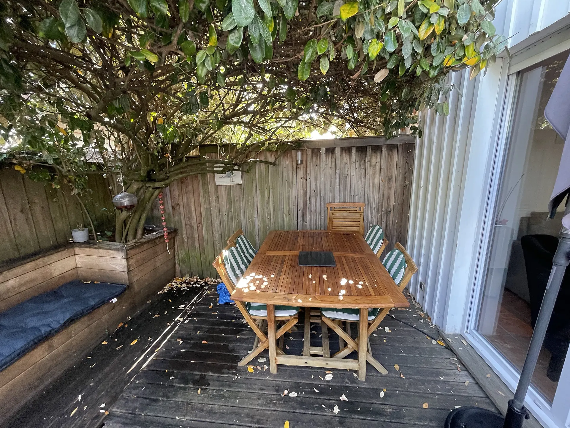 La table de jardin en teck, six couverts, à l’ombre de l’arbre de la terrasse